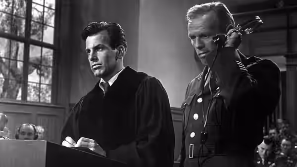 Hans Rolfe (Maximilian Schell) standing at the defense table with an officer