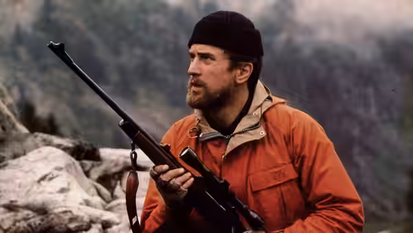 Michael Vronsky (Robert De Niro) holding rifle on rocky mountain slope