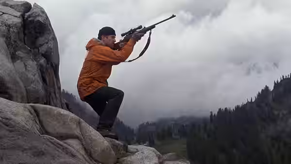 Michael Vronsky (Robert De Niro) aiming a rifle from rocky outcrop