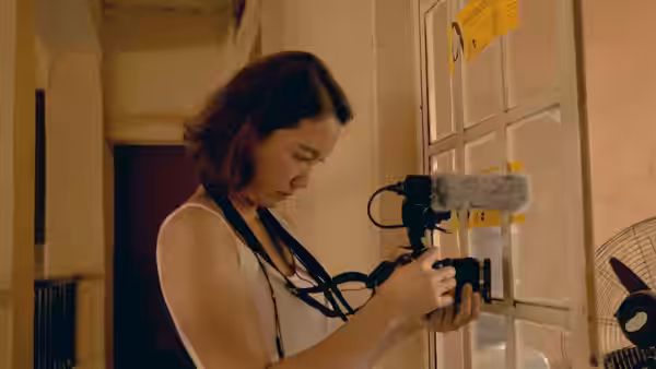 Shiori Itō adjusts a camera rig in a warmly lit room