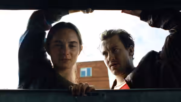 A young woman and man lean over an open container, looking inside