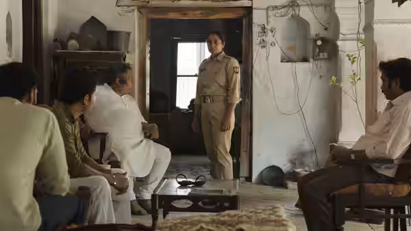Constable Santosh Saini (Shahana Goswami) stands in a doorway as men sit inside a modest room