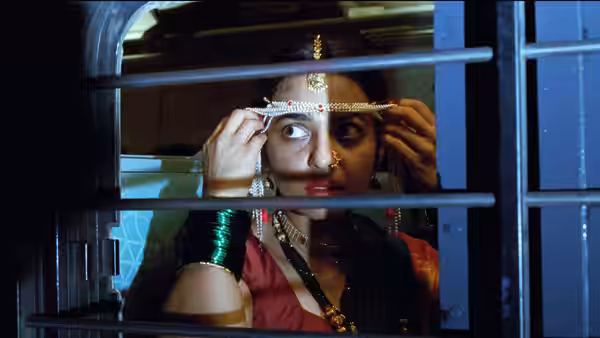 Uma (Radhika Apte) adjusts her bridal headpiece behind a barred window