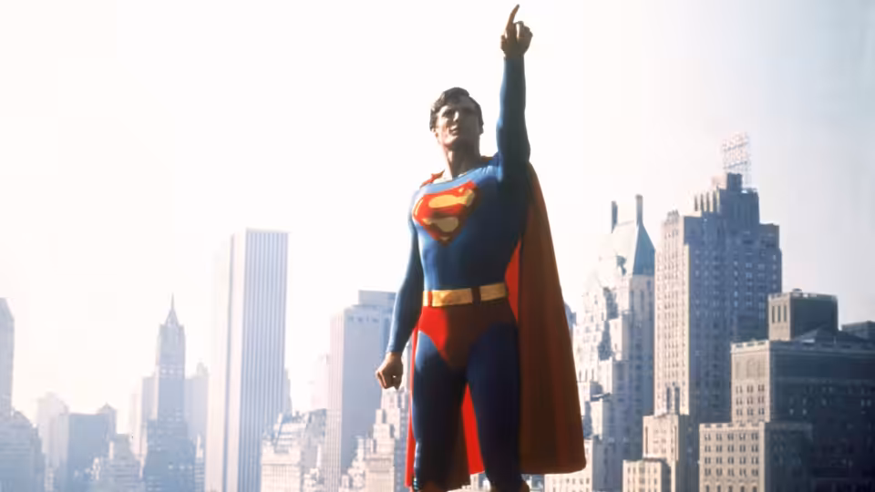 Christopher Reeve as Superman raises a hand above the New York City skyline