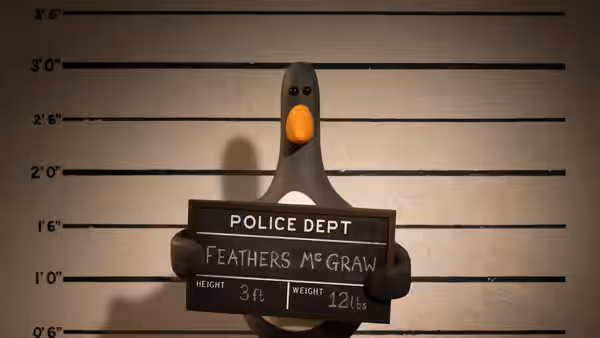 Feathers McGraw poses for a police lineup beneath a height chart