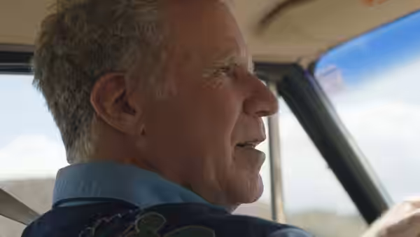 Will Ferrell looks ahead from the passenger seat of a moving car