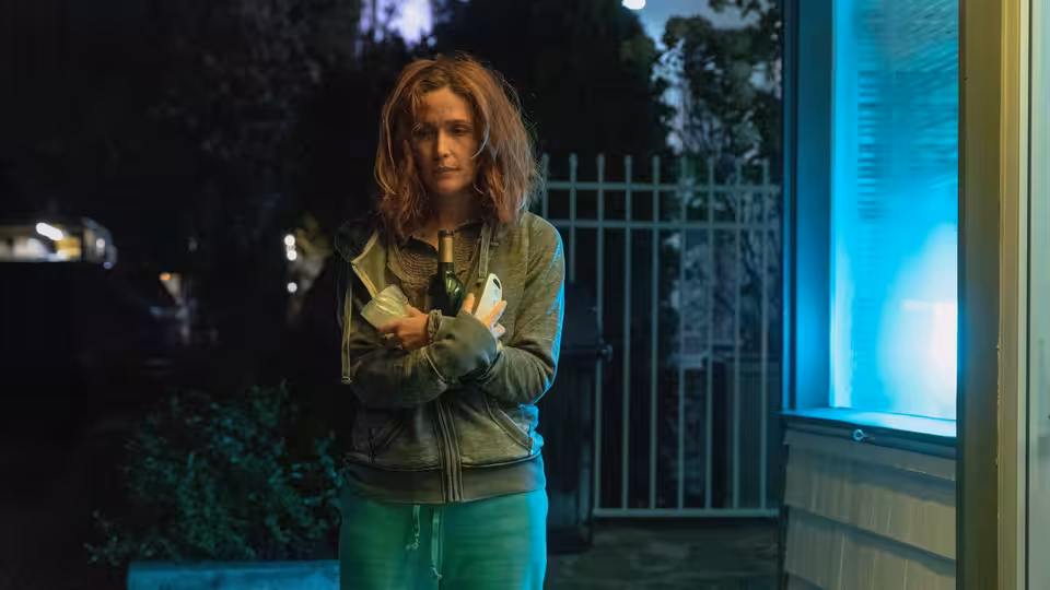 Linda (Rose Byrne) stands outside at night, clutching several items against her chest