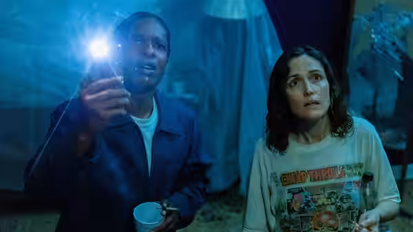 James (A$AP Rocky) shines a flashlight while Linda (Rose Byrne) looks ahead inside a dim room