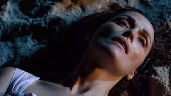 Linda (Rose Byrne) lies on rocky ground, looking upward with tearful eyes