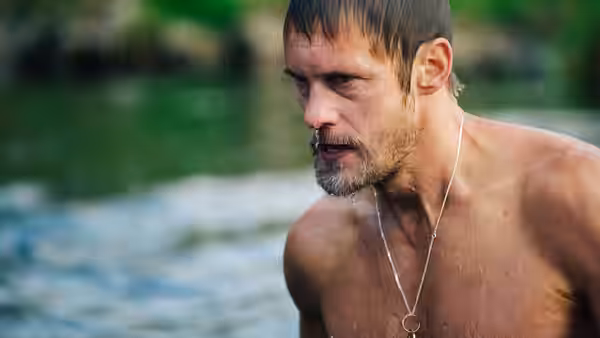 Ray (Alexander Skarsgård), shirtless and wearing a pendant, stands beside a river