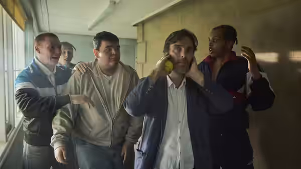 Steve holds a tennis ball as boys gather around him in a hallway