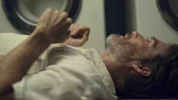 Steve lies on the floor with his hands raised beside a washing machine