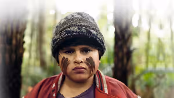 Ricky (Julian Dennison) with face paint standing among trees