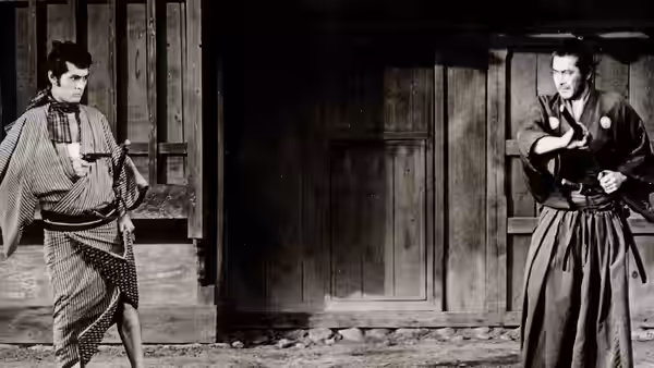 Two men face off outside a wooden building, one drawing a pistol