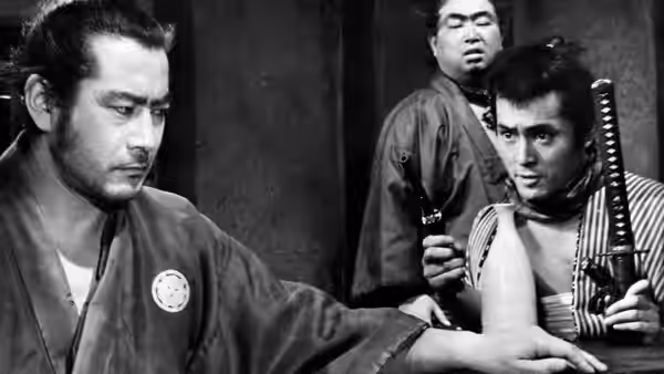 Stern samurai extends his arm while two men stand behind him indoors