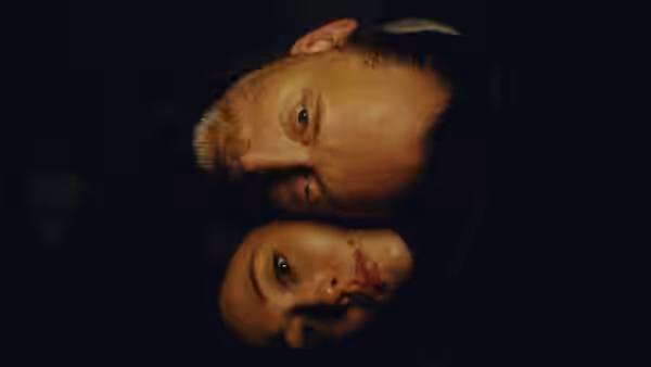 A man and woman lie close together, their faces turned sideways in the darkness