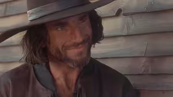 John Proctor (Daniel Day-Lewis) stands in a broad-brimmed hat beside a wooden wall