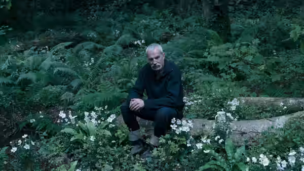 Ray Stoker (Daniel Day-Lewis) sits among ferns and white wildflowers in the woods