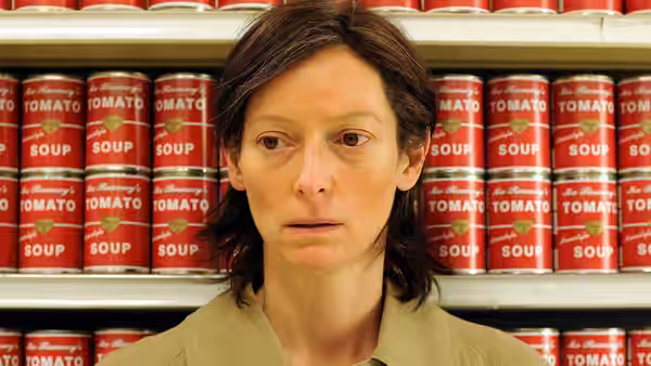 Eva (Tilda Swinton) standing before shelves stocked with tomato soup cans