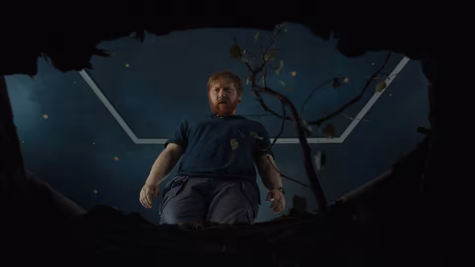 Jon (Rupert Grint) peers down into a dark pit beneath a geometric ceiling