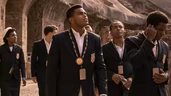 A young man wearing a medal walks with classmates in school blazers
