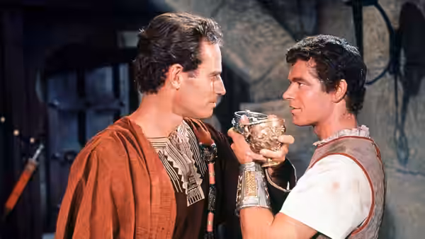 Judah Ben-Hur (Charlton Heston) faces Messala (Stephen Boyd) holding an ornate cup