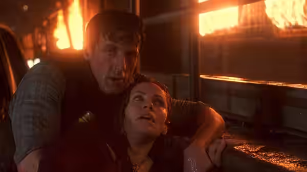 Kit Latura (Sylvester Stallone) supports an injured woman beside a burning vehicle