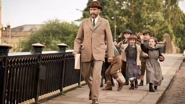 Dr. Henry Guthrie (Ralph Fiennes) walks along a riverside path as children follow behind