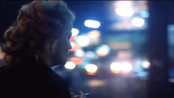 A person in profile faces a row of blurred, colorful lights