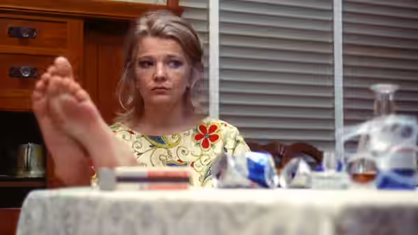 Mabel Longhetti (Gena Rowlands) sits at a dining table with feet raised in the foreground