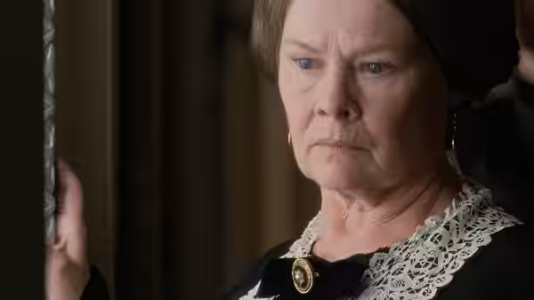 Queen Victoria (Judi Dench) stands by a doorway in mourning dress, looking gravely ahead