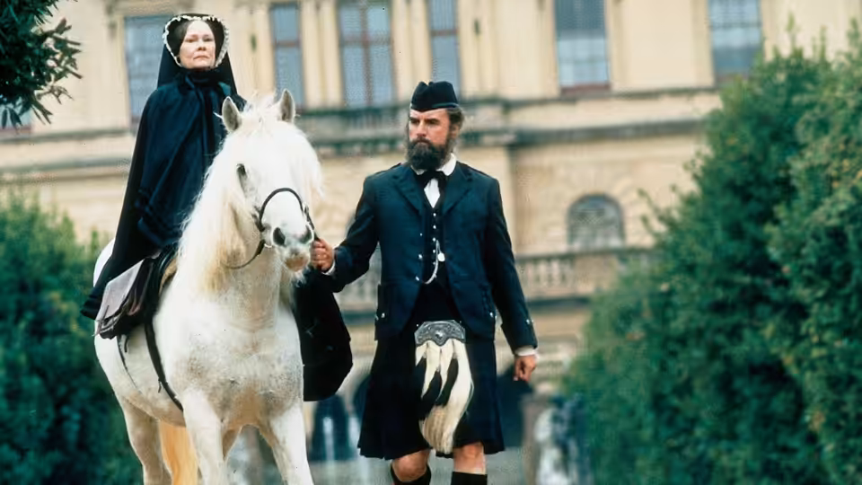Queen Victoria (Judi Dench) rides behind John Brown (Billy Connolly), who leads her white horse outside a palace