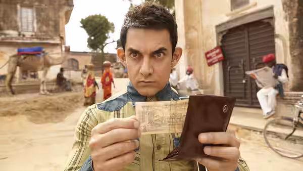 Aamir Khan as PK checking a wallet and currency on a village street