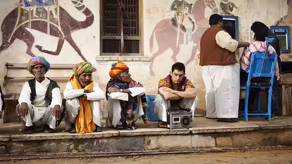 Men in traditional clothes sitting on steps beside a painted wall