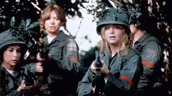 Judy Benjamin (Goldie Hawn) aims her rifle among fellow recruits in the woods