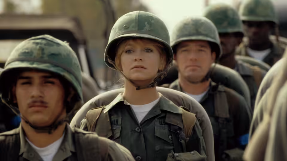 Judy Benjamin (Goldie Hawn) stands in formation with helmeted soldiers