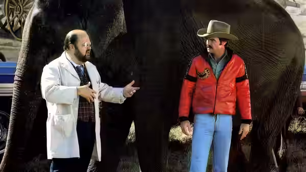 Doc (Dom DeLuise) gestures beside Bandit (Burt Reynolds) in front of an elephant