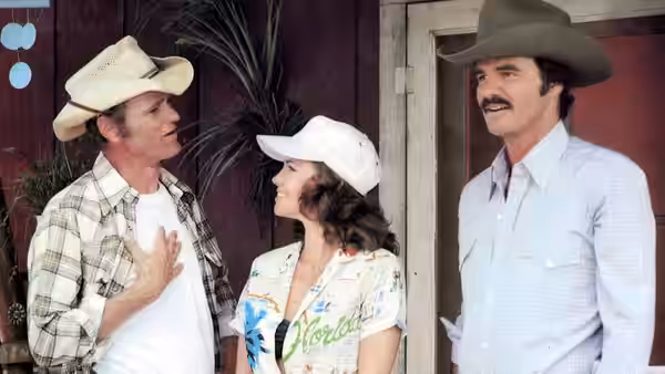 Cledus (Jerry Reed), Carrie (Sally Field), and Bandit (Burt Reynolds) stand outside a building