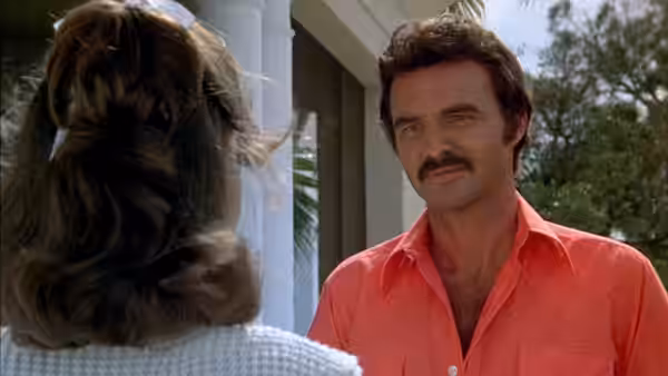 Bandit (Burt Reynolds) speaks with a woman outside a house