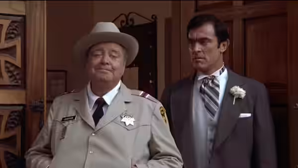 Buford T. Justice (Jackie Gleason) stands beside a suited man in a doorway