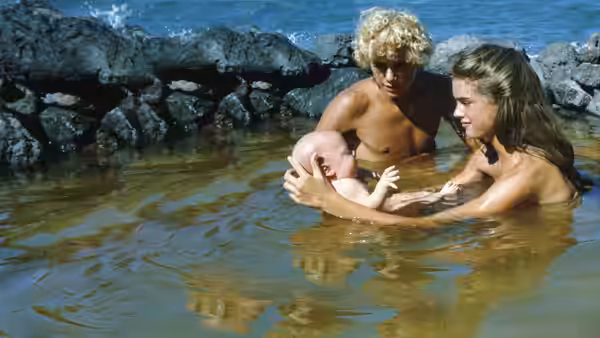 Richard (Christopher Atkins) and Emmeline (Brooke Shields) hold their baby in a tidal pool
