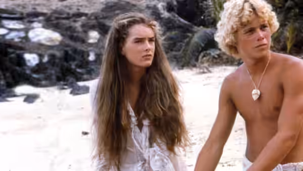 Emmeline (Brooke Shields) and Richard (Christopher Atkins) sit together on the beach