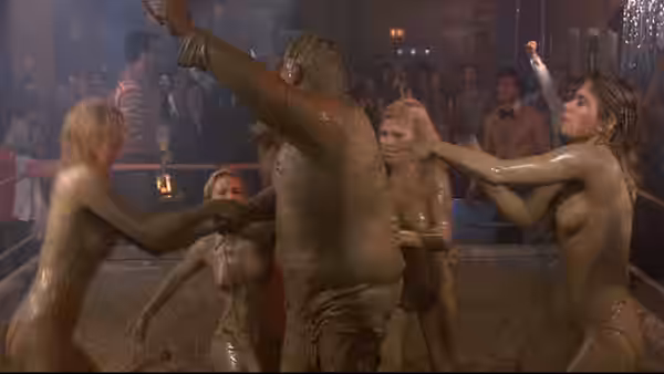 Recruits wrestle and celebrate in a muddy pit as onlookers cheer