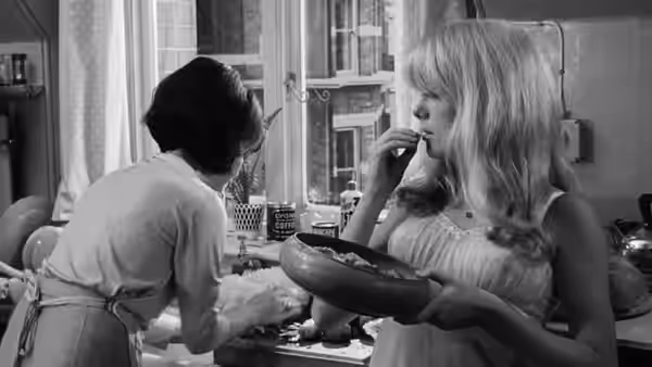 Hélène Ledoux (Yvonne Furneaux) works at the kitchen counter as Carol Ledoux (Catherine Deneuve) holds a bowl
