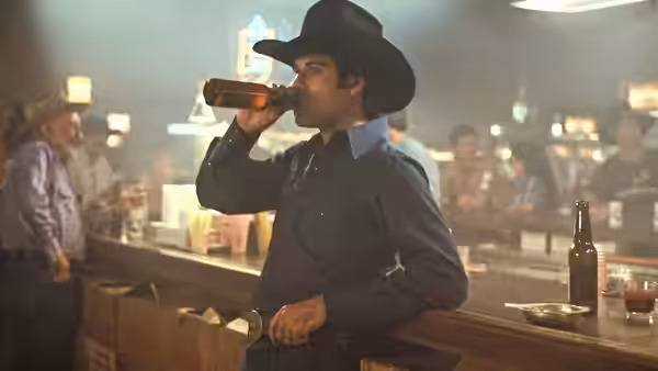 Bud Davis (John Travolta) drinks from a bottle at the honky-tonk bar