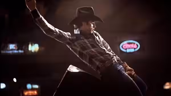 Bud Davis (John Travolta) rides a mechanical bull beneath the lights of a honky-tonk
