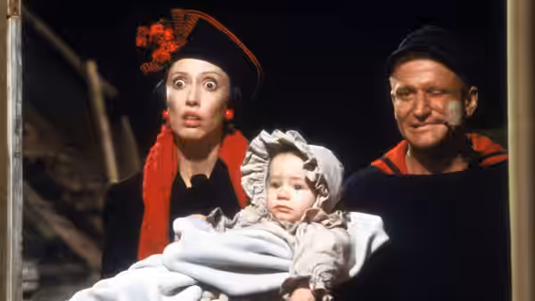 Olive Oyl (Shelley Duvall) and Popeye (Robin Williams) hold their baby in a doorway