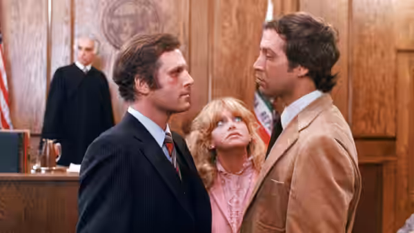 Glenda Parks (Goldie Hawn) stands between Ira Parks (Charles Grodin) and Nick Gardenia (Chevy Chase) in court