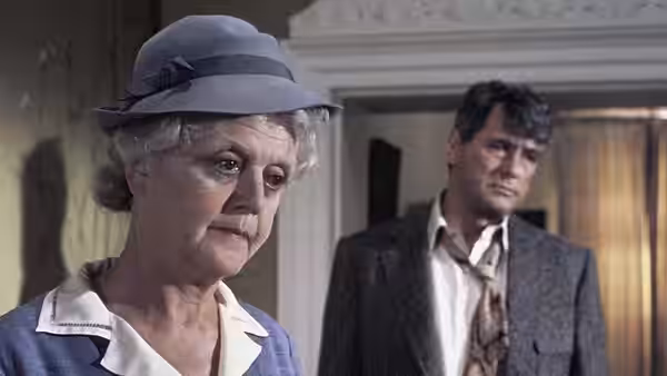 Miss Marple (Angela Lansbury) stands in the foreground as Inspector Craddock (Edward Fox) watches behind her