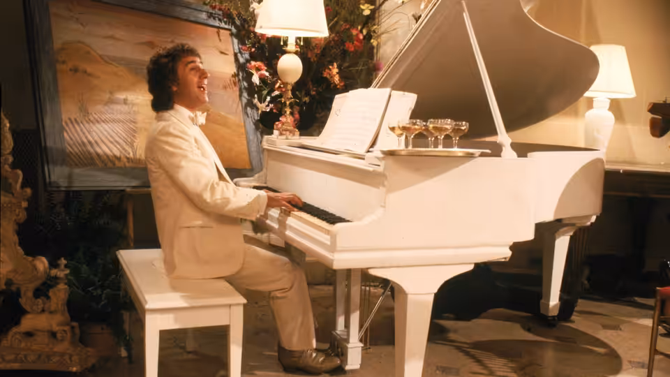 Arthur Bach (Dudley Moore) plays a grand piano in an ornate room
